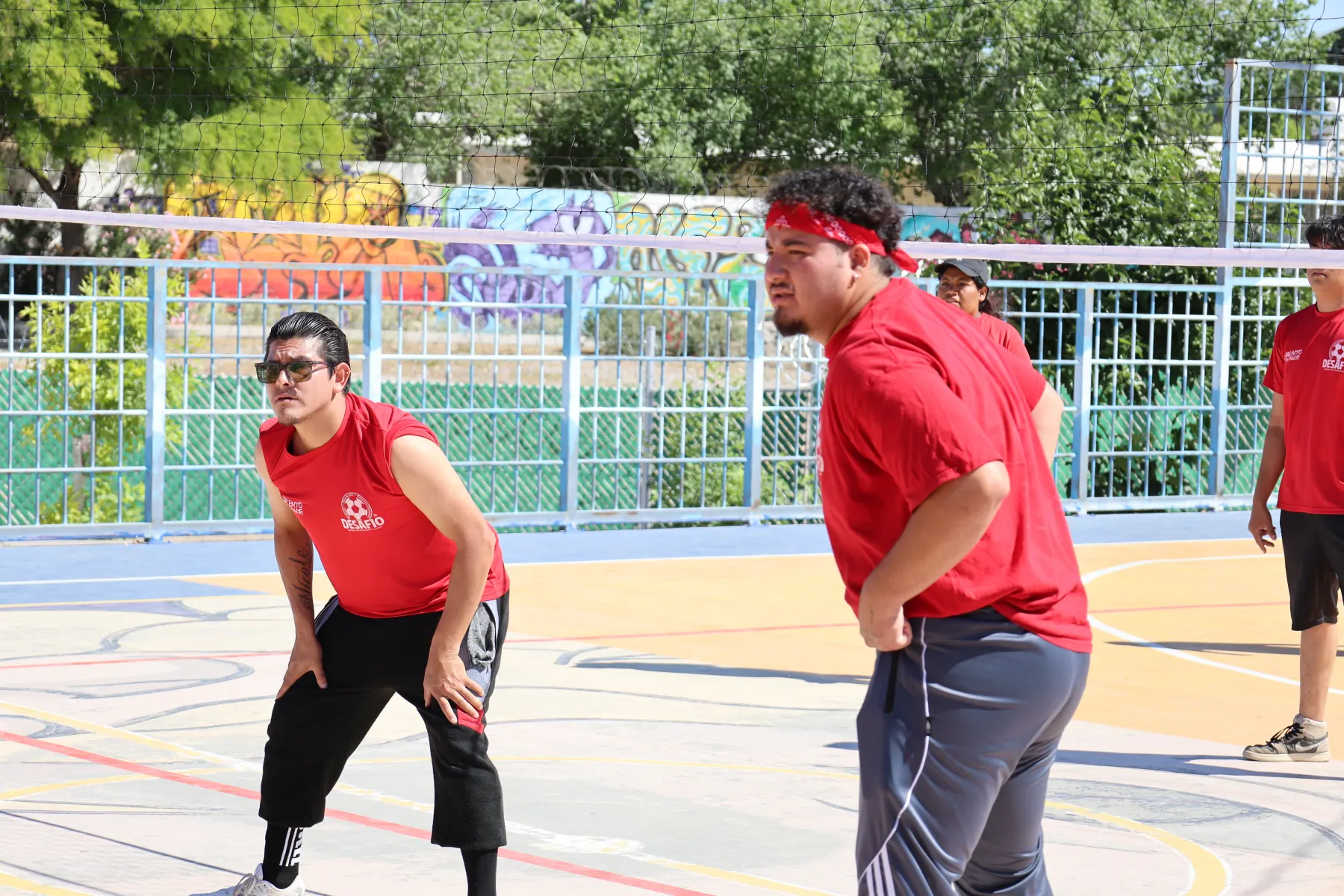Jóvenes con playera roja juegan voleibol en una cancha de colores