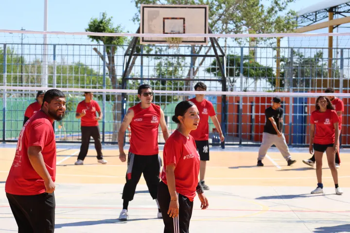 Jóvenes juegan voleibol en una cancha de colores