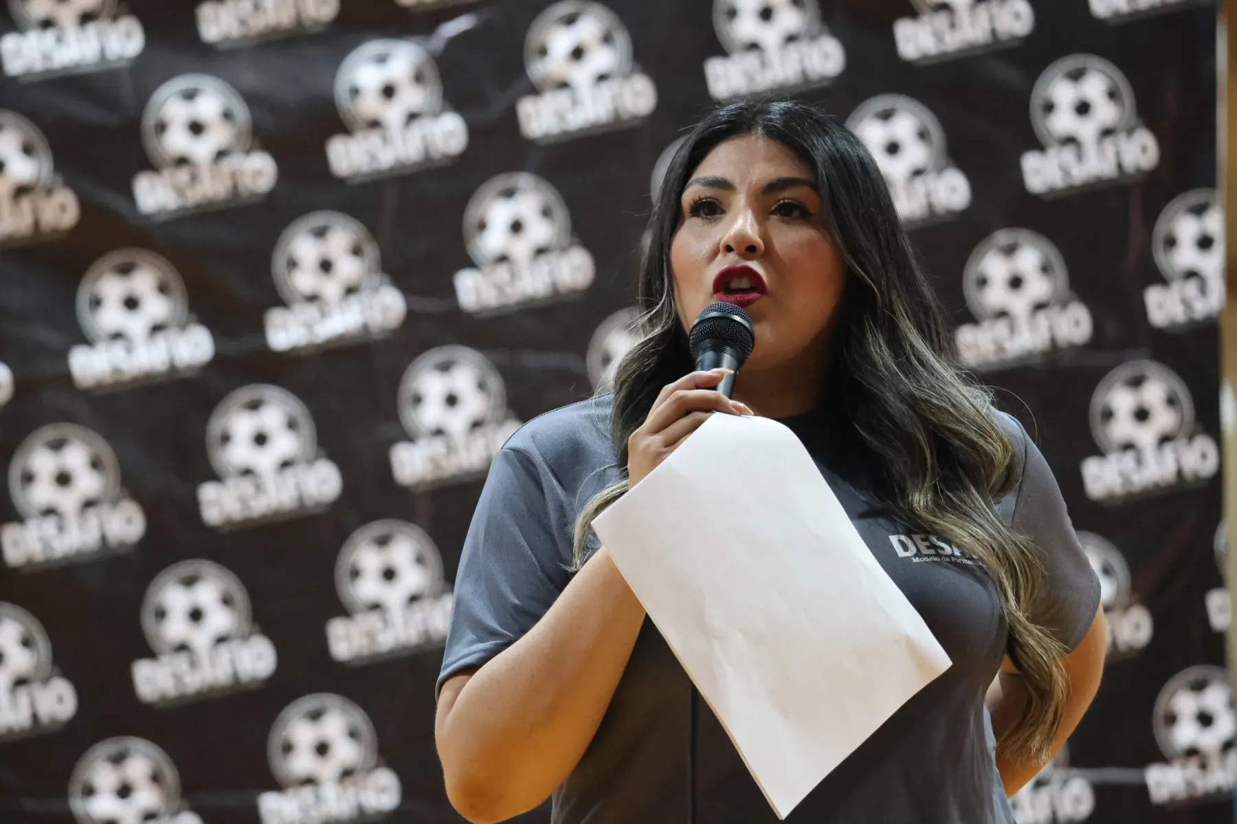 Una joven habla al micrófono frente a un fondo con el balón de Desafío