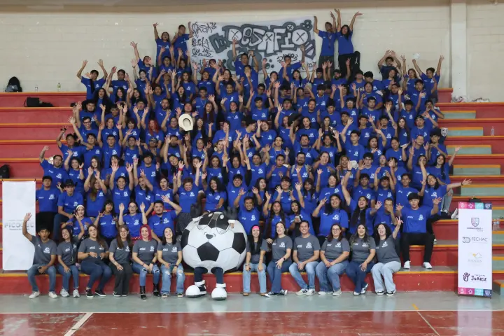 Foto grupal de jóvenes con playeras azules en las gradas