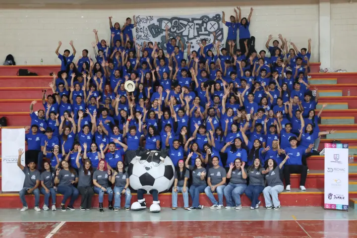 Foto grupal de jóvenes en las gradas con una mascota de balón