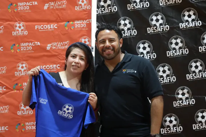 Una pareja sostiene la playera azul de Desafío