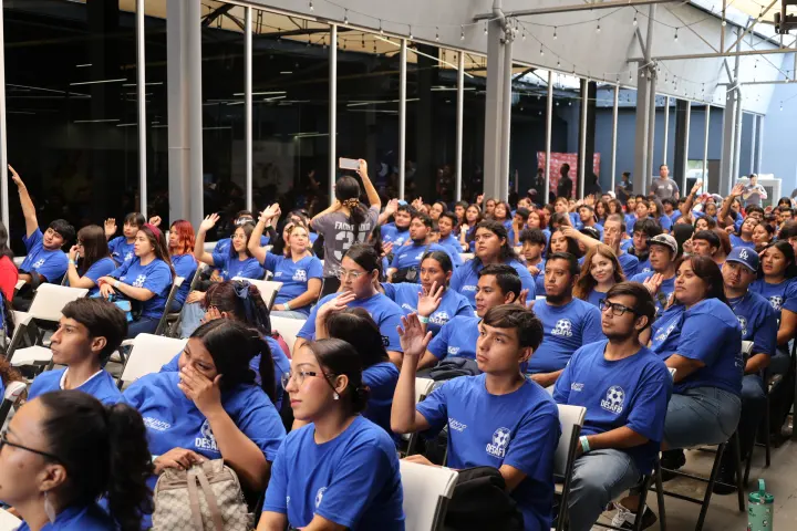 Auditorio lleno de jóvenes con playeras azules